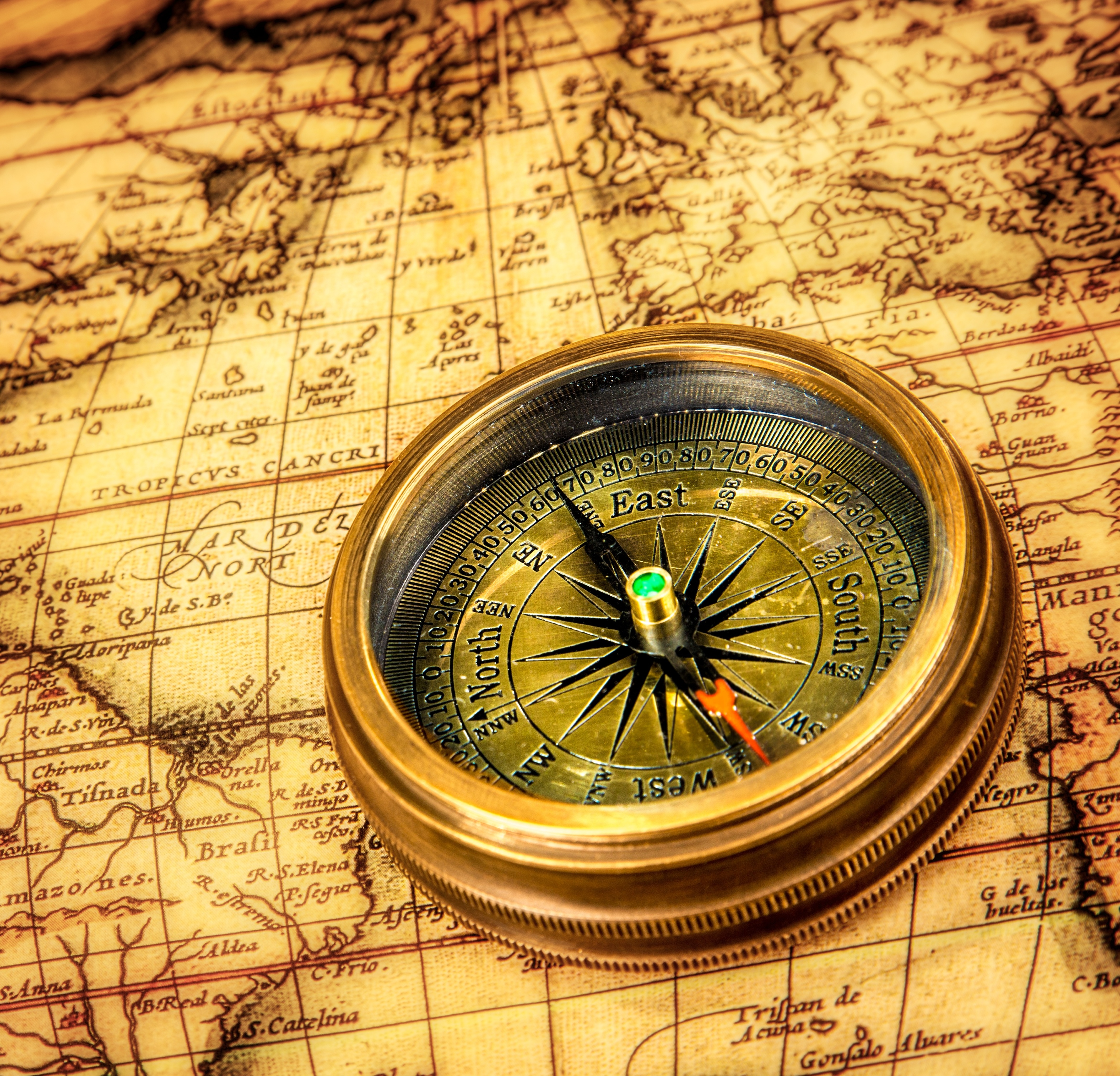 18731117 – vintage still life. vintage compass lies on an ancient world map.