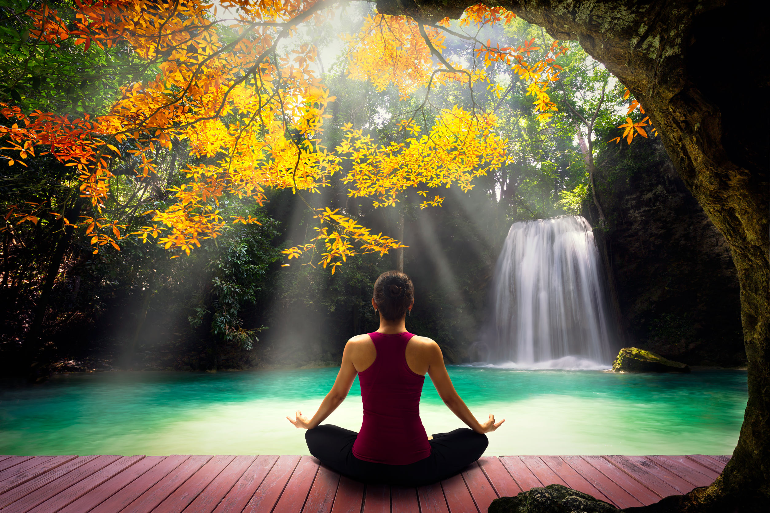 41619177 – young woman in yoga pose sitting near watefall rear view